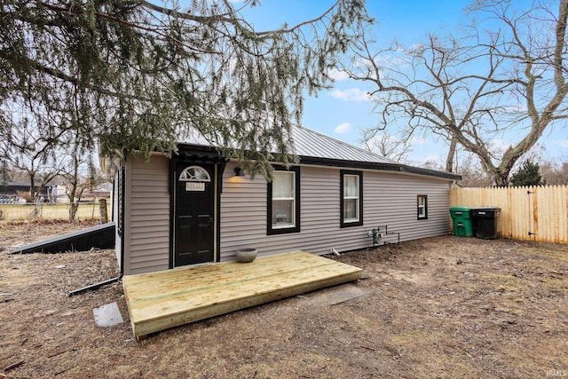 rear view of property with fence and metal roof