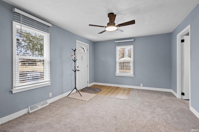 empty room featuring carpet floors, visible vents, baseboards, and a ceiling fan