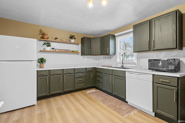 kitchen featuring light countertops, green cabinets, light wood-style floors, a sink, and white appliances