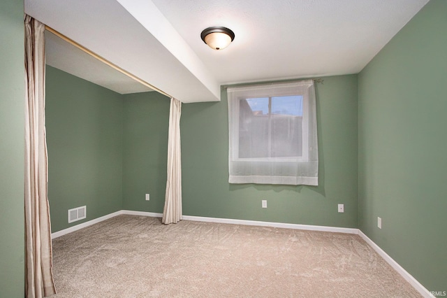 carpeted spare room with visible vents and baseboards