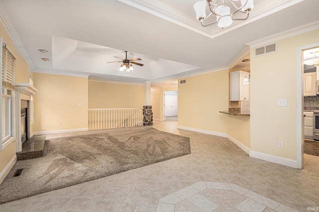 unfurnished living room featuring visible vents, baseboards, ornamental molding, a tiled fireplace, and a raised ceiling