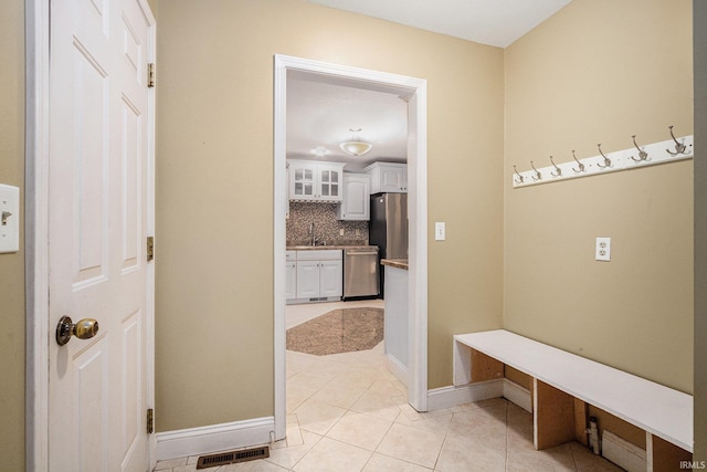 mudroom with light tile patterned floors, a sink, visible vents, and baseboards