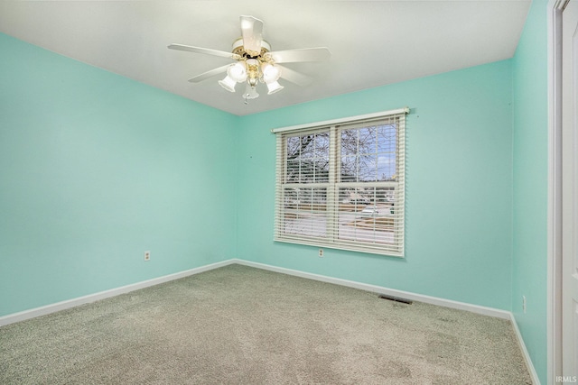 carpeted spare room featuring visible vents, a ceiling fan, and baseboards