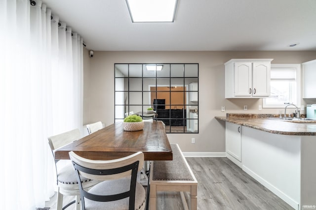 dining space featuring light wood-type flooring and baseboards