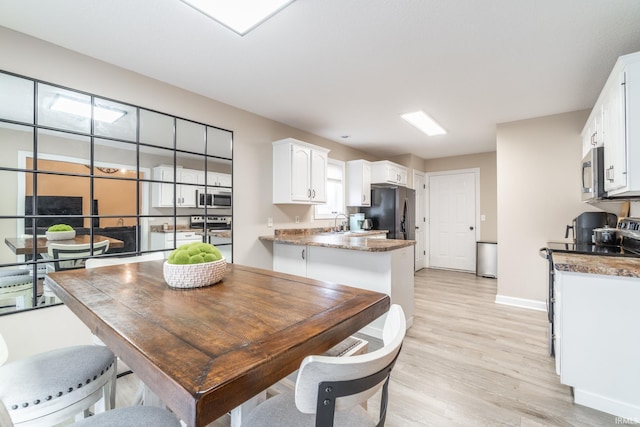 dining area with baseboards and light wood finished floors