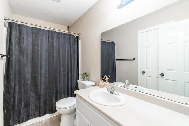 full bath with toilet, vanity, a textured ceiling, wood finished floors, and a shower with curtain