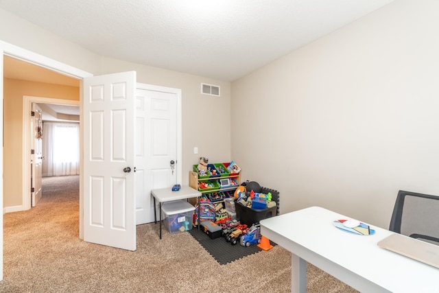 recreation room featuring light colored carpet, visible vents, and a textured ceiling