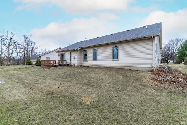 rear view of house with a deck, a yard, and a shingled roof