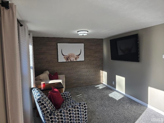 sitting room featuring carpet floors, an accent wall, wood walls, and baseboards