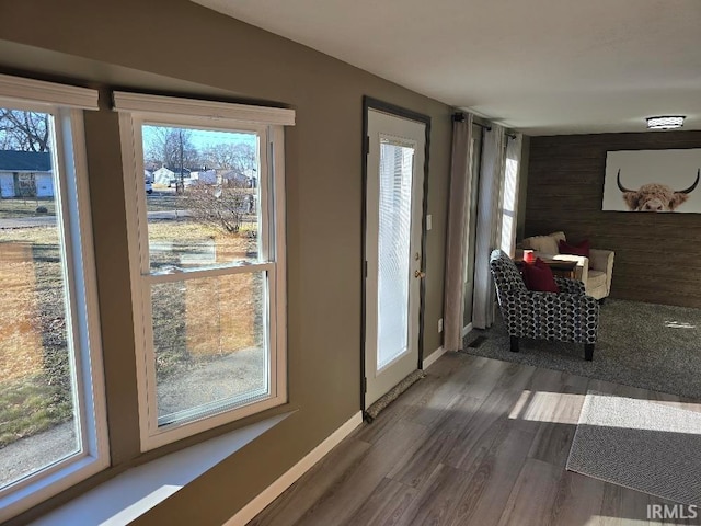 doorway with baseboards, wood finished floors, and wooden walls