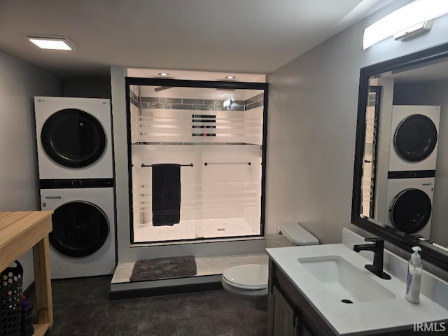 full bathroom featuring toilet, vanity, stacked washing maching and dryer, tile patterned floors, and a stall shower