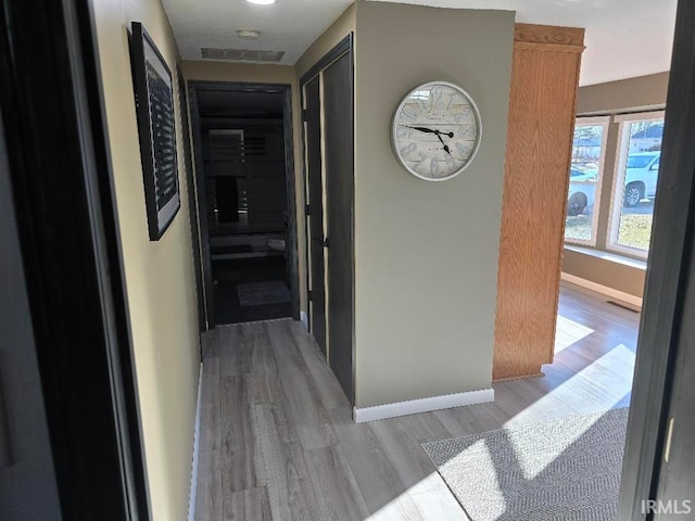 corridor featuring light wood-style flooring and baseboards