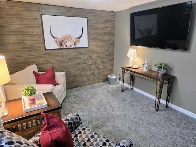 living area featuring carpet floors, wood walls, an accent wall, and baseboards