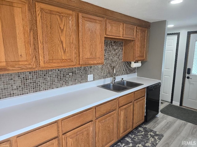 kitchen with a sink, light countertops, backsplash, brown cabinets, and dishwasher