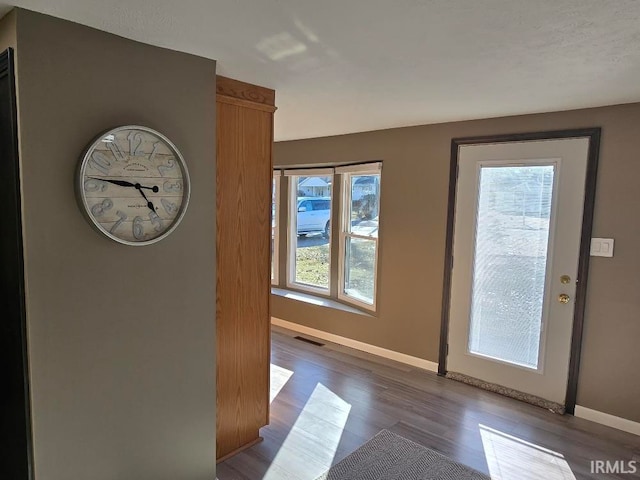 doorway featuring visible vents, baseboards, and wood finished floors