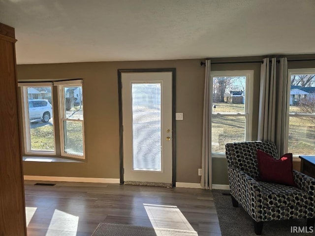 doorway to outside featuring dark wood-style floors, baseboards, and visible vents