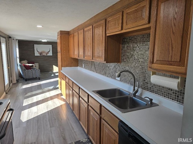 kitchen with range with electric cooktop, brown cabinetry, light countertops, light wood-style floors, and a sink