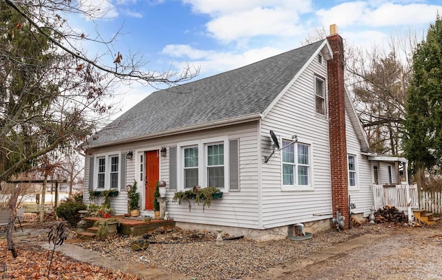 new england style home with a shingled roof and a chimney