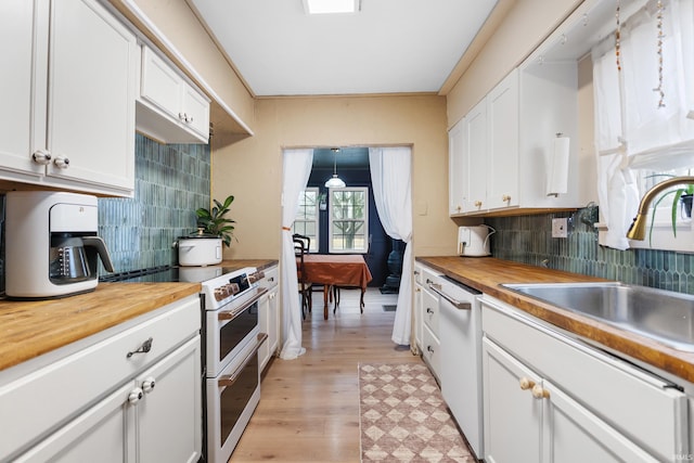 kitchen with a sink, white appliances, wood counters, and white cabinets