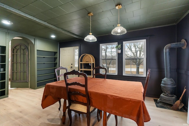 dining area with crown molding, arched walkways, and wood finished floors