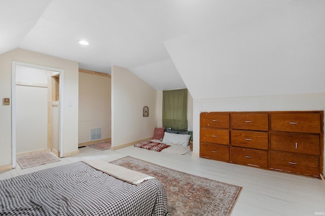 bedroom with light wood-style flooring, visible vents, and vaulted ceiling