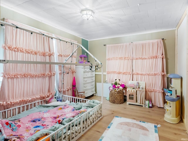 bedroom with crown molding and wood finished floors