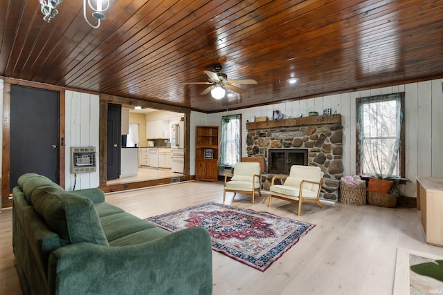 living area with light wood-type flooring, a fireplace, plenty of natural light, and heating unit