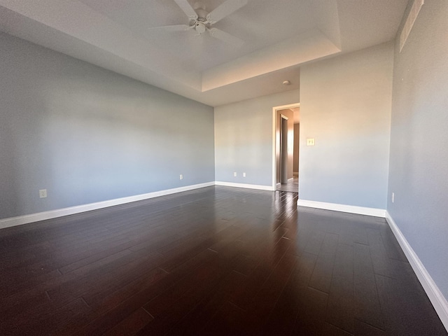 empty room with ceiling fan, dark wood-type flooring, and baseboards