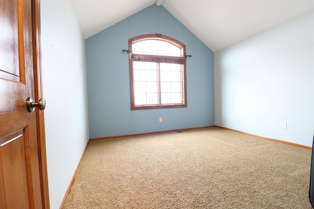 spare room featuring vaulted ceiling, carpet, and baseboards