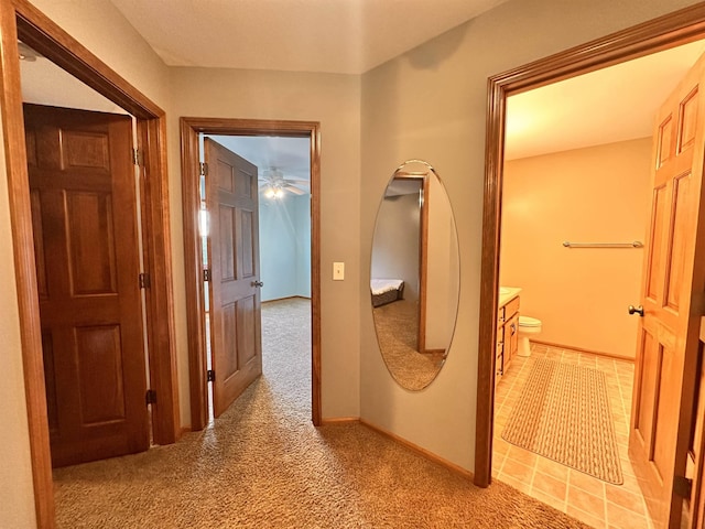 hallway featuring light carpet and baseboards