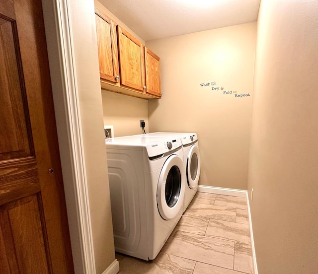 clothes washing area featuring cabinet space, washing machine and dryer, marble finish floor, and baseboards