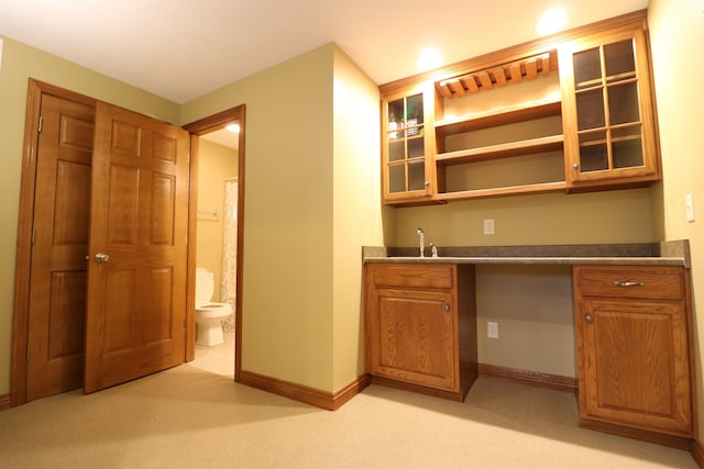 bar featuring light colored carpet, a sink, and baseboards