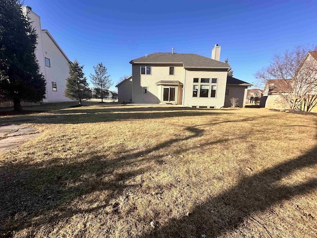 rear view of property featuring a chimney and a lawn