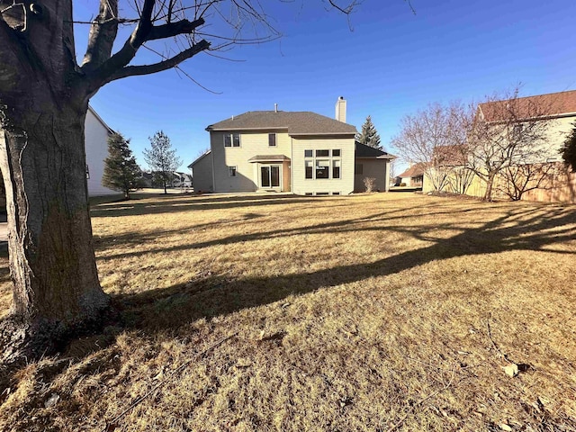 rear view of property featuring a yard and a chimney