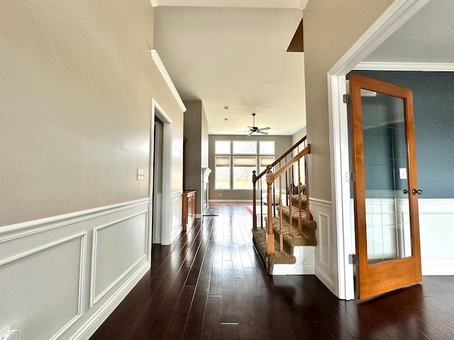 interior space featuring wainscoting, stairway, dark wood-style flooring, crown molding, and a decorative wall