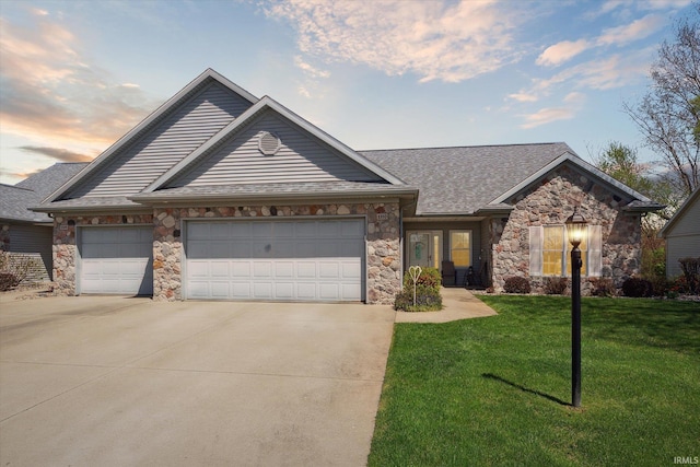 view of front of house featuring stone siding, concrete driveway, a yard, and an attached garage