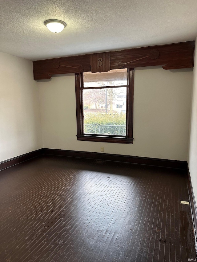 spare room with wood-type flooring, baseboards, and a textured ceiling