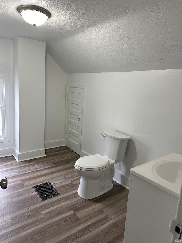 bathroom featuring visible vents, vaulted ceiling, toilet, and wood finished floors