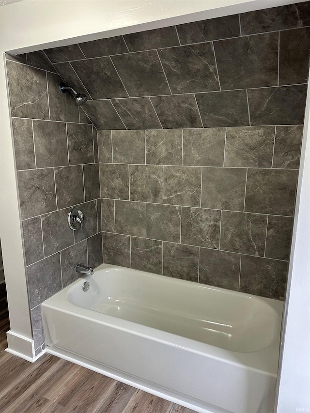 full bath featuring shower / washtub combination and wood finished floors