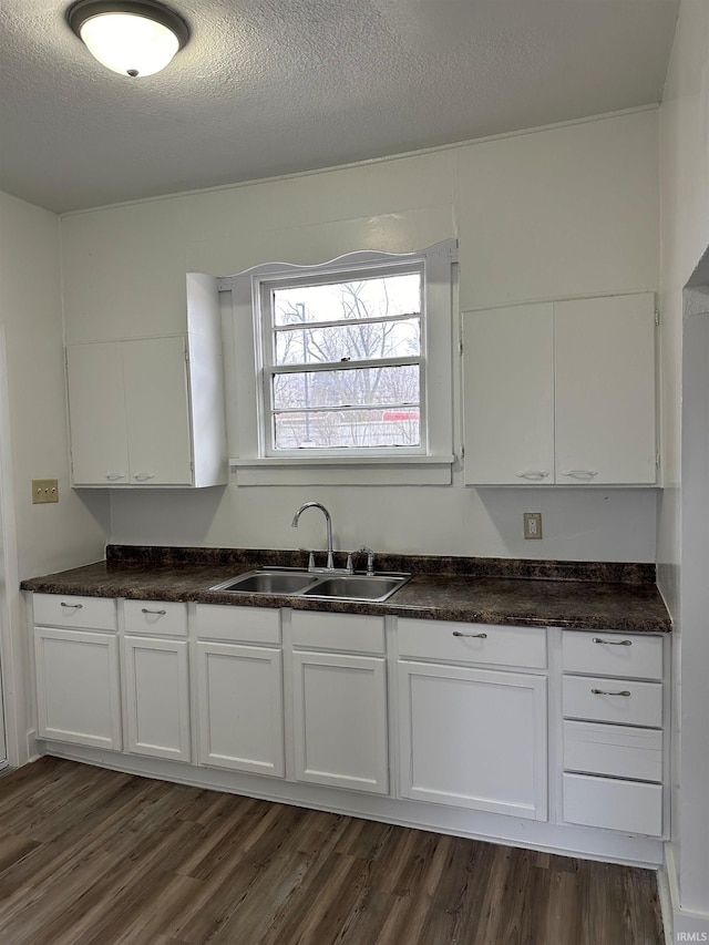 kitchen with dark wood-style floors, white cabinetry, and a sink