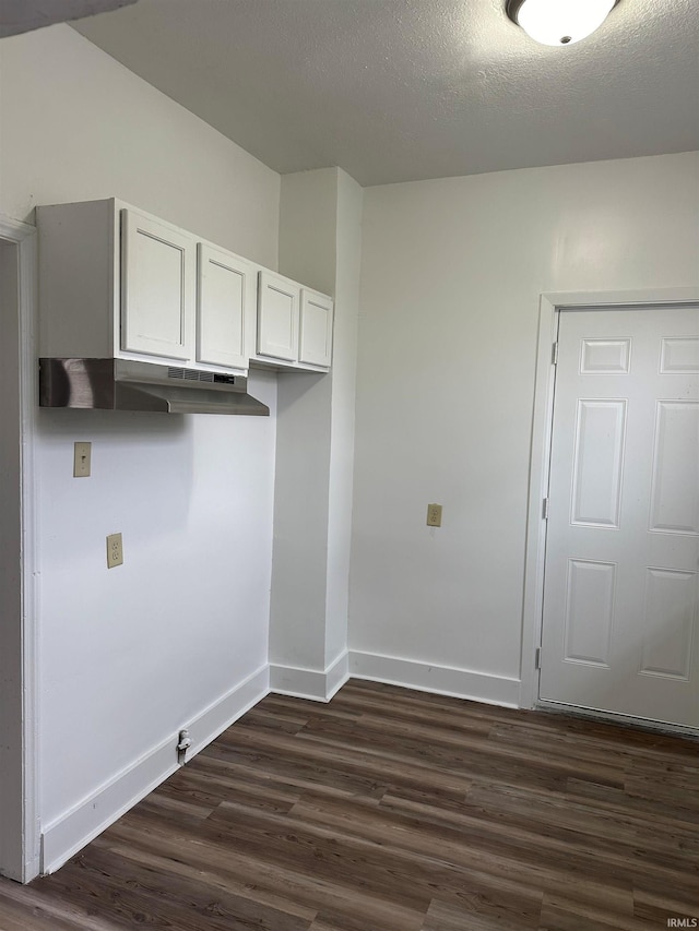 clothes washing area with dark wood-type flooring, a textured ceiling, and baseboards