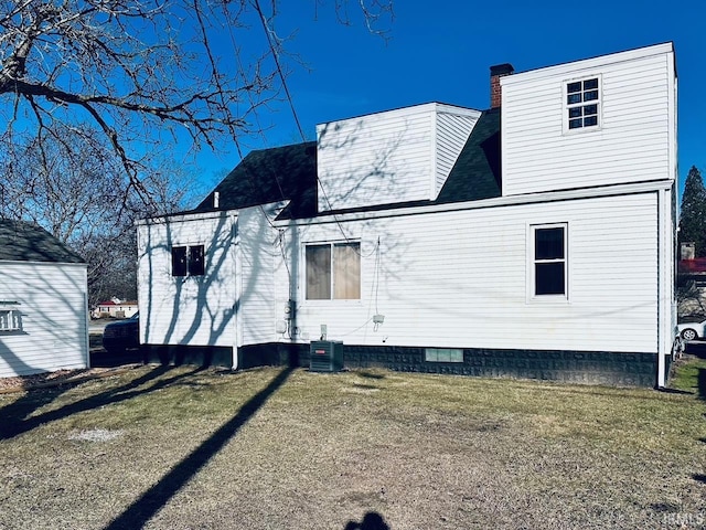 back of house with a yard, central AC unit, and a chimney