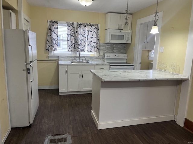 kitchen featuring a peninsula, white appliances, a sink, and white cabinetry