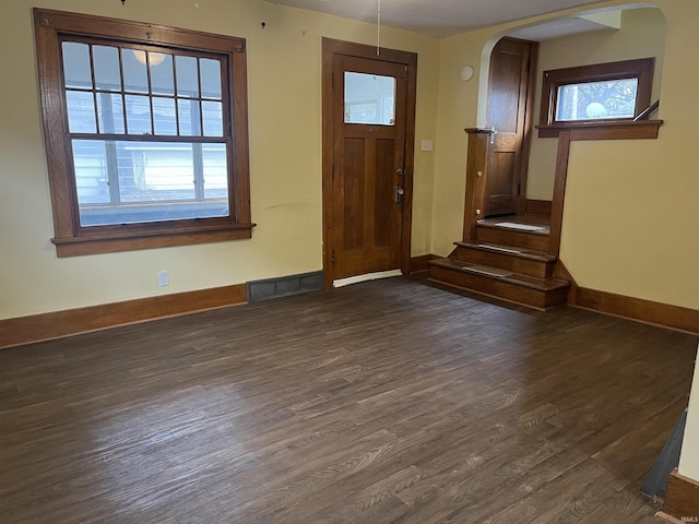 entryway featuring arched walkways, dark wood-style flooring, visible vents, and baseboards