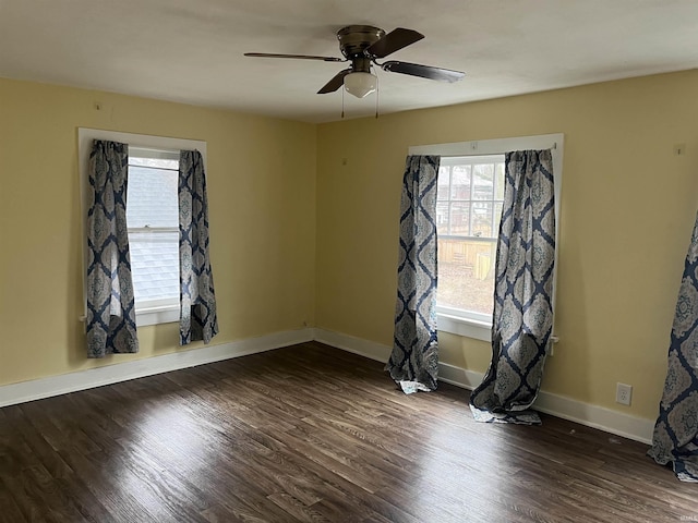 empty room featuring dark wood-style floors, ceiling fan, and baseboards