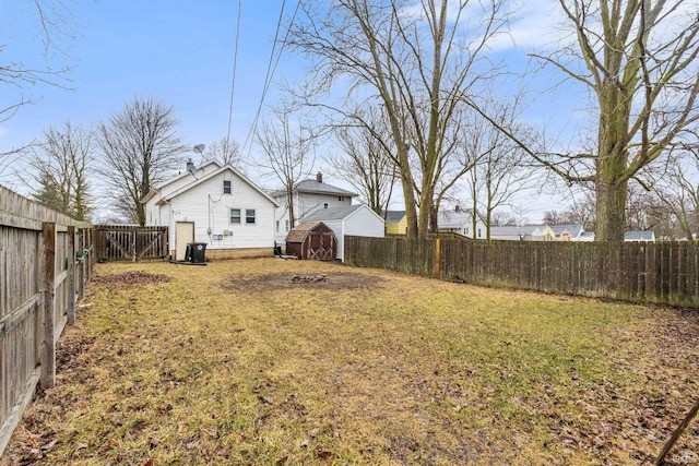 view of yard with an outbuilding, a shed, cooling unit, and a fenced backyard