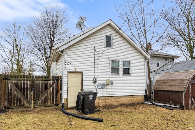 rear view of property featuring a lawn, a gate, a storage unit, fence, and an outdoor structure