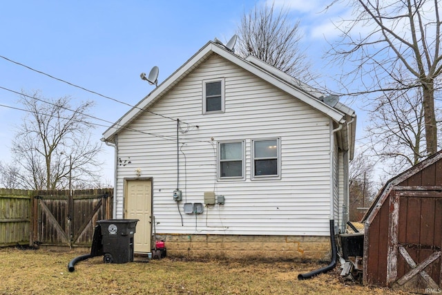 back of property with a shed, fence, and an outbuilding