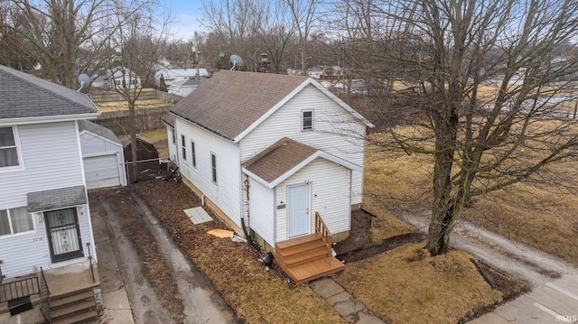 view of front facade with driveway, entry steps, a garage, roof with shingles, and an outdoor structure