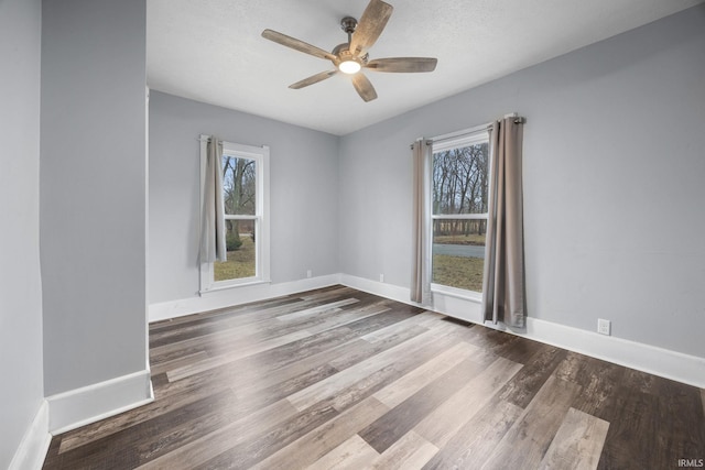 unfurnished room with a ceiling fan, visible vents, baseboards, and wood finished floors